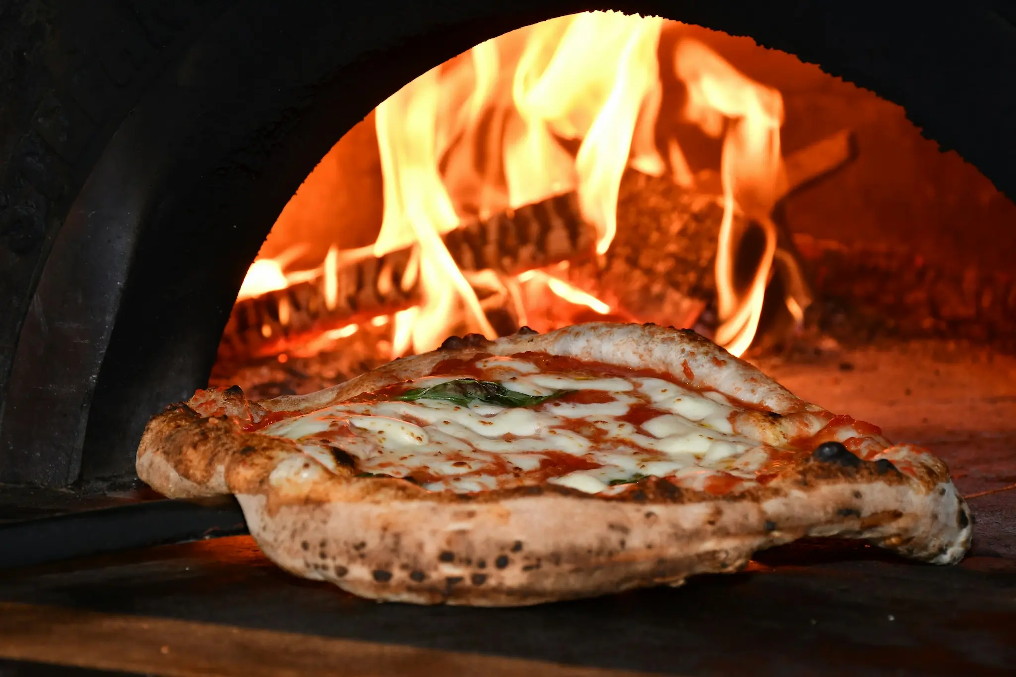 A pizza baking in a wood oven